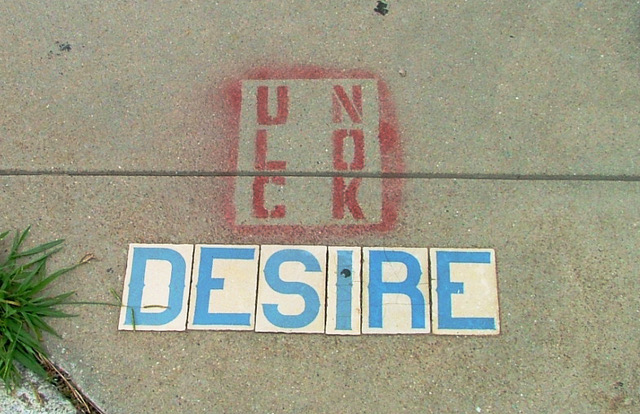 letters spraypainted on sidewalk with the word desire beneath