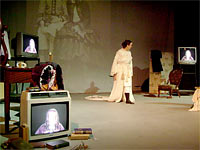 Neri dressed as EBB addressing video image of herself